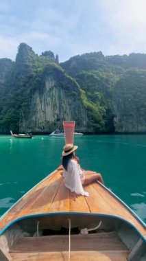 Taylandlı kadınlar, Pileh Lagoon 'da uzun kuyruklu bir teknenin önünde, Koh Phi Phi Tayland' da yeşil zümrüt okyanusu olan, sabahları lagündeki uzun kuyruklu bir teknenin önündeki kadınlar.