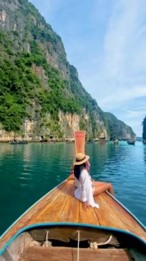 Taylandlı kadınlar, Pileh Lagoon 'da uzun kuyruklu bir teknenin önünde, Koh Phi Phi Tayland' da yeşil zümrüt okyanusu olan, sabahları lagündeki uzun kuyruklu bir teknenin önündeki kadınlar.