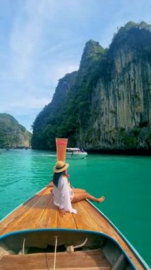 Koh Phi Phi Tayland, Taylandlı kadınlar Pileh lagünündeki uzun kuyruklu teknenin önünde yeşil zümrüt okyanusla Koh Phi Tayland 'da, uzun kuyruklu bir teknenin önünde kadınlar.