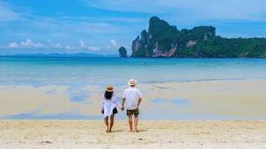 Bir çift erkek ve sabah güneşinde kumsalda yürüyen kadınlar. Dalum Plajı Koh Phi Phi Tayland