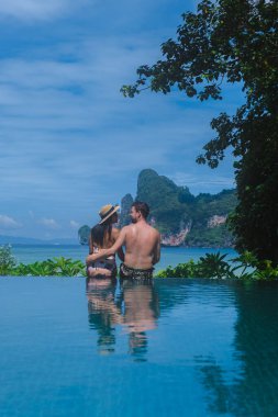 Sonsuzluk havuzunda bir çift kadın ve erkek Koh Phi Tayland sahiline bakıyorlar.
