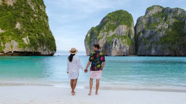 Taylandlı kadınlar ve beyaz erkekler Maya Körfezi sahilinde yürüyorlar Koh Phi Tayland
