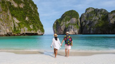 Maya Körfezi plajında yürüyen bir çift kadın ve erkek sabahleyin turkuaz renkli okyanusla Koh Phi Phi Tayland 'da. 