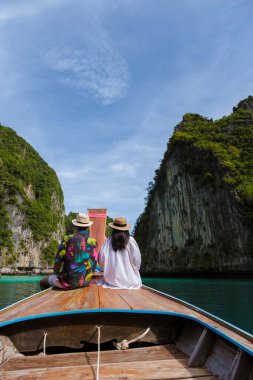 Koh Phi Tayland gölünde, uzun kuyruklu bir teknenin önünde birkaç Taylandlı kadın ve beyaz adam. Pileh Gölü Tayland Koh Phi Phi