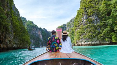 Koh Phi Tayland gölünde, uzun kuyruklu bir teknenin önünde birkaç Taylandlı kadın ve beyaz adam. Pileh Gölü Tayland Koh Phi Phi