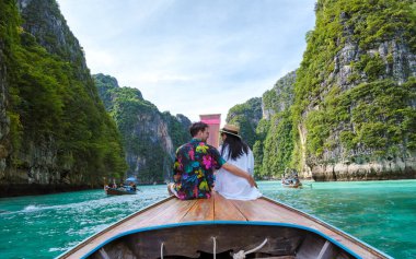 Couple in front of a Longtail boat at the lagoon of Koh Phi Phi Thailand clipart