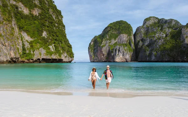 当天早上 一对夫妇在海滩上散步 看着镜头 泰国妇女和高加索男子带着草皮色的大海在玛雅湾海滩上散步 — 图库照片