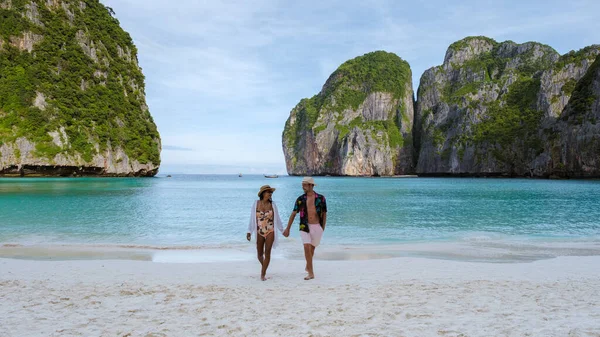 当天早上 一对夫妇在海滩上散步 看着镜头 泰国妇女和高加索男子带着草皮色的大海在玛雅湾海滩上散步 — 图库照片