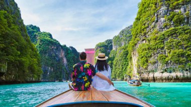 Tatil sırasında Koh Phi Phi Tayland gölünde uzun kuyruklu teknenin önündeki çift.