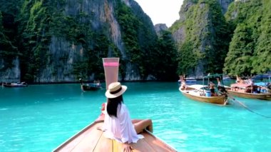 Koh Phi Phi Tayland 'da yeşil zümrüt okyanuslu Pileh Lagoon, uzun kuyruklu teknenin önünde şapkalı kadınlar.
