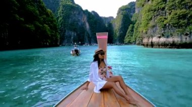 Taylandlı kadınlar Pileh lagünündeki uzun kuyruklu teknenin önünde Koh Phi Tayland 'da yeşil zümrüt okyanusuyla, 