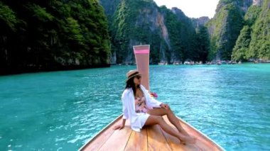 Taylandlı kadınlar Pileh lagünündeki uzun kuyruklu teknenin önünde Koh Phi Tayland 'da yeşil zümrüt okyanusuyla, 