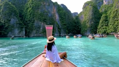 Koh Phi Phi Tayland 'da yeşil zümrüt okyanuslu Pileh Lagoon, Taylandlı kadınlar uzun kuyruklu teknenin önünde.