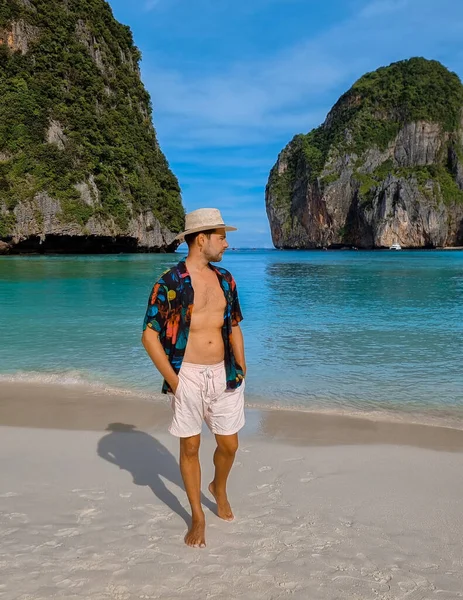 young men with swim shorts and a hat on the beach of Maya Bay Koh Phi Phi Thailand.
