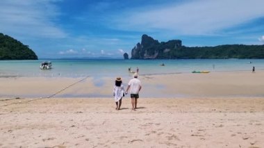 Koh Phi Phi 'nin sabah güneşinde sahilde yürüyen bir çift kadın ve erkek. Dalum Plajı Koh Phi Phi 