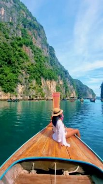 Taylandlı kadınlar Pileh lagünündeki uzun kuyruklu teknenin önünde Koh Phi Tayland 'da yeşil zümrüt okyanusla,