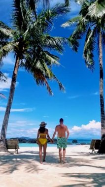 Tayland, Koh Kham Adası Trat 'ta palmiye ağaçları olan tropikal bir adada bir çift kadın ve erkek. 