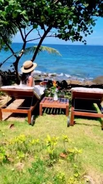 Asyalı kadınlar, Koh Kood Tayland tropikal adasında şarap içerek okyanusun kenarında dinleniyorlar..