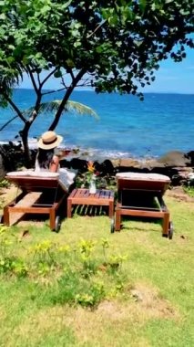 Asyalı kadınlar, Koh Kood Tayland tropikal adasında şarap içerek okyanusun kenarında dinleniyorlar..