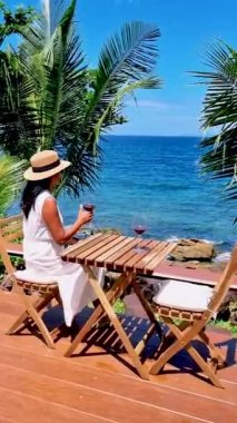 Asyalı kadınlar, Koh Kood Tayland tropikal adasında şarap içerek okyanusun kenarında dinleniyorlar..