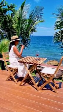 Asyalı kadınlar, Koh Kood Tayland tropikal adasında şarap içerek okyanusun kenarında dinleniyorlar..
