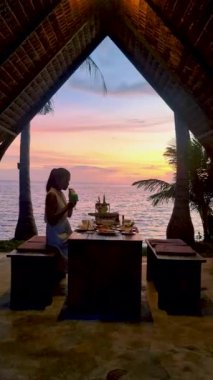 Gün batımında Asyalı Taylandlı kadınlar tatil sırasında Koh Chang Tayland sahilinde yemek yiyorlar.