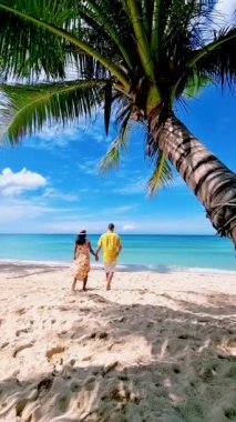 Koh Kood Tayland adasında tatilde olan birkaç erkek ve kadın. Beyaz tropikal sahilde palmiye ağaçları sallanıyor. Mavi okyanusta birkaç erkek ve kadın Tayland 'da tatilde.