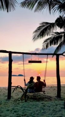 Tayland Koh Chang Adası 'ndaki bir salıncaktan gün batımını izleyen bir çift kadın ve erkek.. 