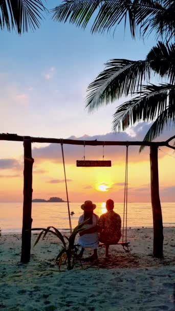 Par Hombres Mujeres Viendo Puesta Sol Playa Desde Columpio Tailandia — Vídeo de stock