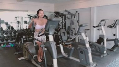 Sağlıklı kalmak için spor bisikleti süren mutlu, formda olgun bir kadın. Orta yaşlı Asyalı kadınlar spor salonunda kapalı alanda spor yapıyor..