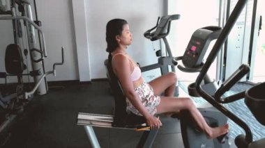 Sağlıklı kalmak için spor bisikletleriyle bisiklete binen mutlu, formda ve olgun kadınların olduğu spor salonunda orta yaşlı kadınların olduğu yere yakın durun..