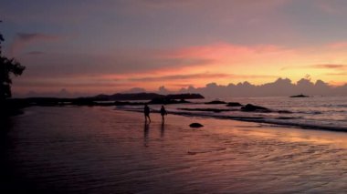İnsanlar gün batımında Khao Lak Tayland sahillerinde yürürler.. 