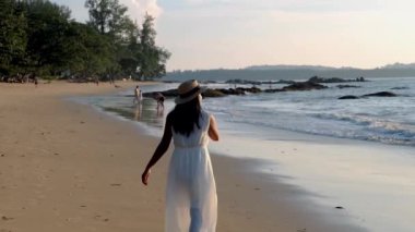 Taylandlı kadınlar Khao Lak Tayland 'da gün batımında sahilde yürürler.. 