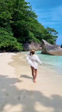 Taylandlı bir kadın Similan Adaları Tayland 'da denizde dev kaya kütleleri olan beyaz bir kumsalda ve turkuaz renkli bir okyanusta. 