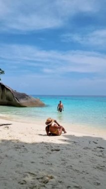 Similan Adaları Tayland 'da denizde dev kaya kütleleri olan beyaz bir kumsalda ve turkuaz renkli bir okyanusta birkaç kadın ve erkek.. 