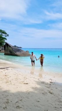 Similan Adaları Tayland 'da denizde dev kaya kütleleri olan beyaz bir kumsalda ve turkuaz renkli bir okyanusta bir çift kadın ve erkek. Tayland tatili