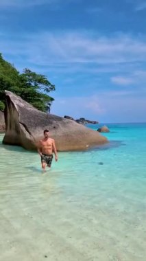 Similan Adaları Tayland 'da denizde dev kaya kütleleri olan beyaz bir kumsalda ve turkuaz renkli bir okyanusta yüzen genç adamlar.. 