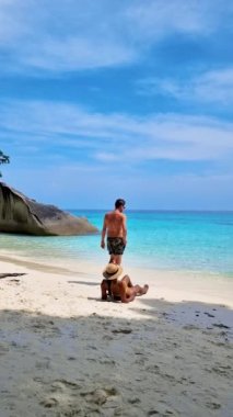 Similan Adaları Tayland 'ın Phangnga eyaletinde denizde dev kaya kütleleri olan beyaz bir kumsalda ve turkuaz renkli bir okyanusta bir çift kadın ve erkek.