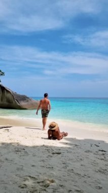 Similan Adaları Tayland 'da denizde dev kaya kütleleri olan beyaz bir kumsalda ve turkuaz renkli bir okyanusta birkaç kadın ve erkek.. 