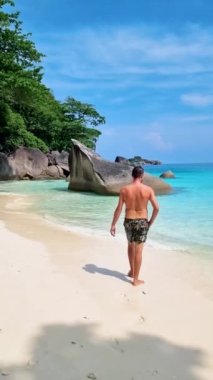 Similan Adaları Tayland 'da denizde dev kaya kütleleri olan beyaz bir kumsalda ve turkuaz renkli bir okyanusta yüzen genç adamlar.. 