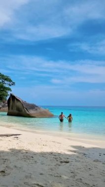 Birkaç erkek ve kadın Similan Adaları Tayland 'da beyaz bir plajda ve turkuaz renkli bir okyanusta. 