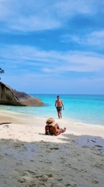 Similan Adaları Tayland 'ın Phangnga eyaletinde denizde dev kaya kütleleri olan beyaz bir kumsalda ve turkuaz renkli bir okyanusta bir çift kadın ve erkek.