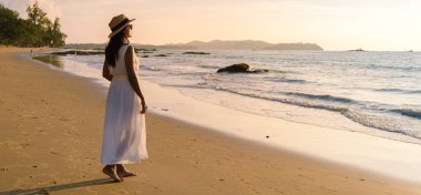 Taylandlı Asyalı kadınlar Khao Lak Tayland 'da gün batımında sahilde yürürler.. 