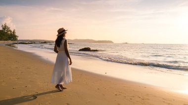 Taylandlı kadınlar Khao Lak Tayland 'da gün batımında sahilde yürürler.. 