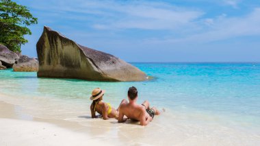 Similan Adaları Tayland 'ın turkuvaz renkli okyanusuyla tropikal beyaz sahilde oturan bir çift kadın ve erkek.. 