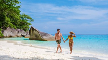 Similan Adaları Tayland 'ın turkuvaz renkli okyanusuyla tropikal beyaz sahilde yürüyen bir çift kadın ve erkek.. 