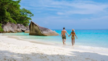 Similan Adaları Tayland 'ın turkuvaz renkli okyanusuyla tropikal beyaz sahilde yürüyen bir çift kadın ve erkek.. 