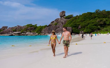 Birkaç erkek ve kadın, Tayland, Similan Adaları 'ndaki tropikal bir sahilde yürüyorlar.. 