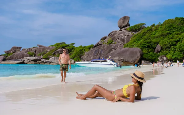 Black women and white men relaxing on the beach in the sun at the Similan Islands in Thailand Phannga