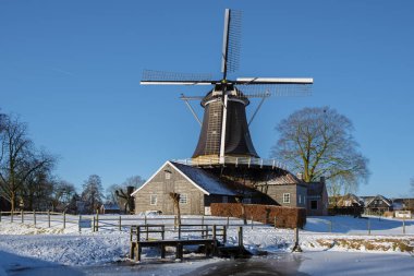 Hollanda 'da kış boyunca kar üzerinde eski tarihi ahşap yel değirmeni. Hollanda 'da kar ve yel değirmeniyle soğuk hava